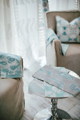 photo of blue sea shells printed on grey fabric lying on small end table