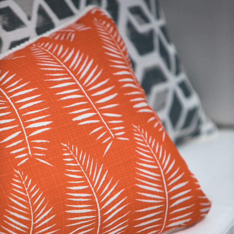 close up picture of outdoor orange fabric with tropical leaf pattern on pillows