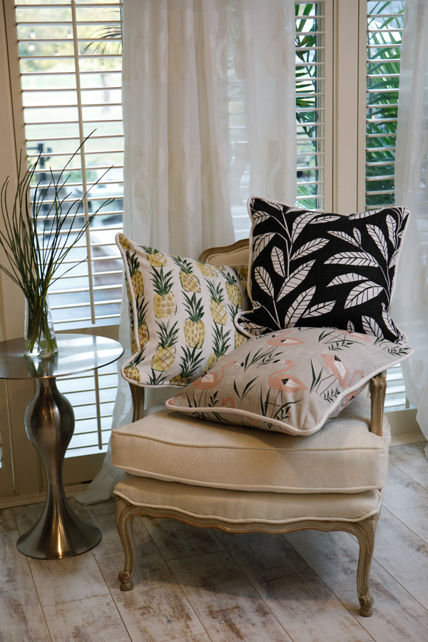 photo of chair and pillows, pillows are made from black foliage and palm leave fabric 
